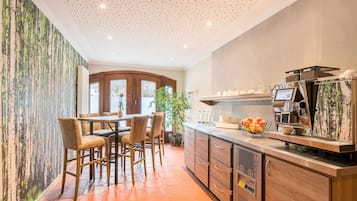 Una cocina moderna con cafetera, taburetes de bar y un ventanal grande.