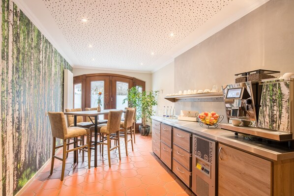 Una cocina moderna con cafetera, taburetes de bar y un ventanal grande.