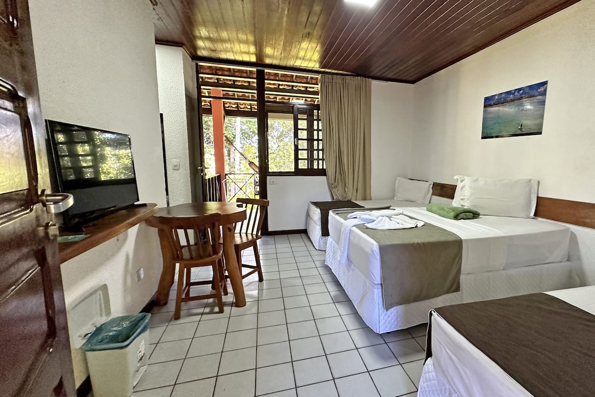 A hotel room with two beds, a desk with a chair, a television, and a window with curtains.