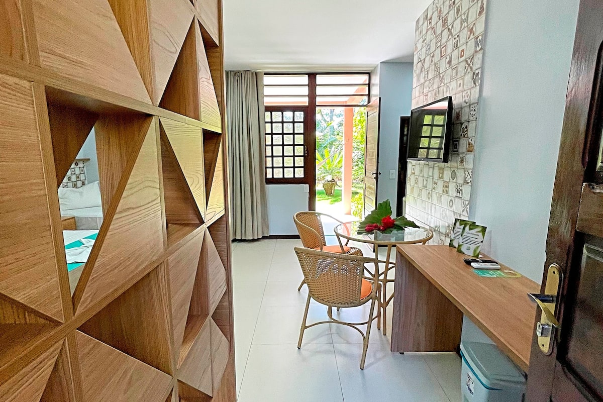 A modern kitchen with a dining area, wooden wall paneling, and a view through the window.