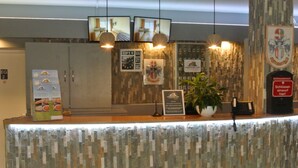A reception desk with a patterned wall, a clock, and a sign indicating the year 2019. - Kemnater Hof Apartments   (Ostfildern)