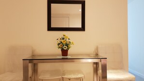 A room with a glass-top table, two chairs, a potted plant, and a mirror on the wall. - 2 BR Condo by JAD at Azure Urban Resort Residences (Parañaque)