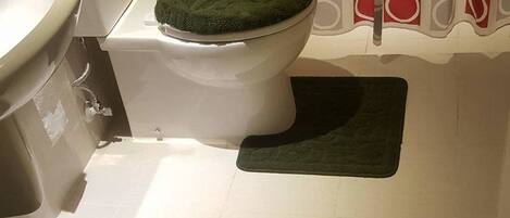 A bathroom with a toilet, sink, and shower area.