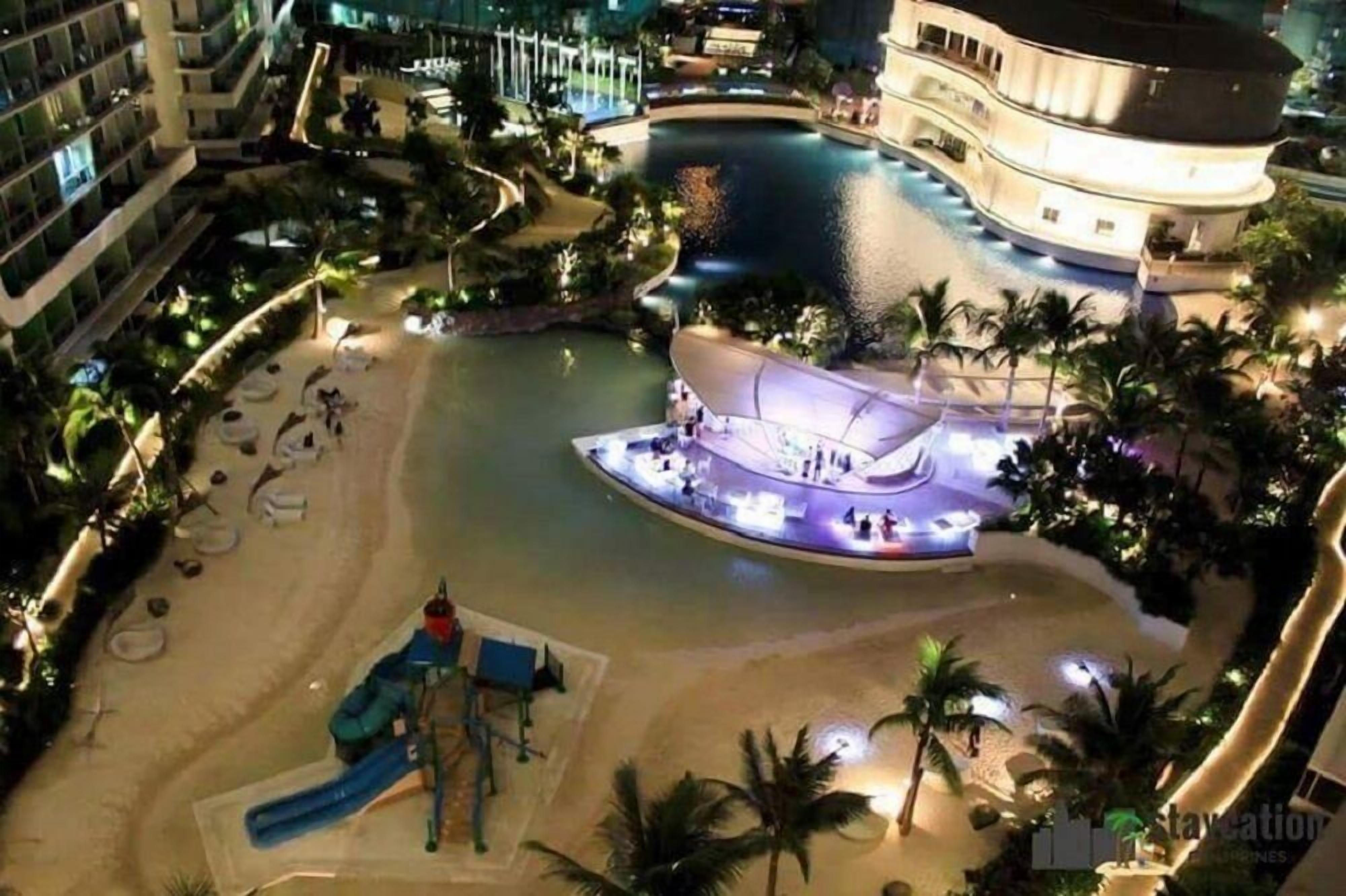 A hotel with a pool, a children's play area, and a beach.