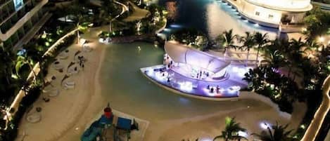 A hotel with a pool, a children's play area, and a beach.