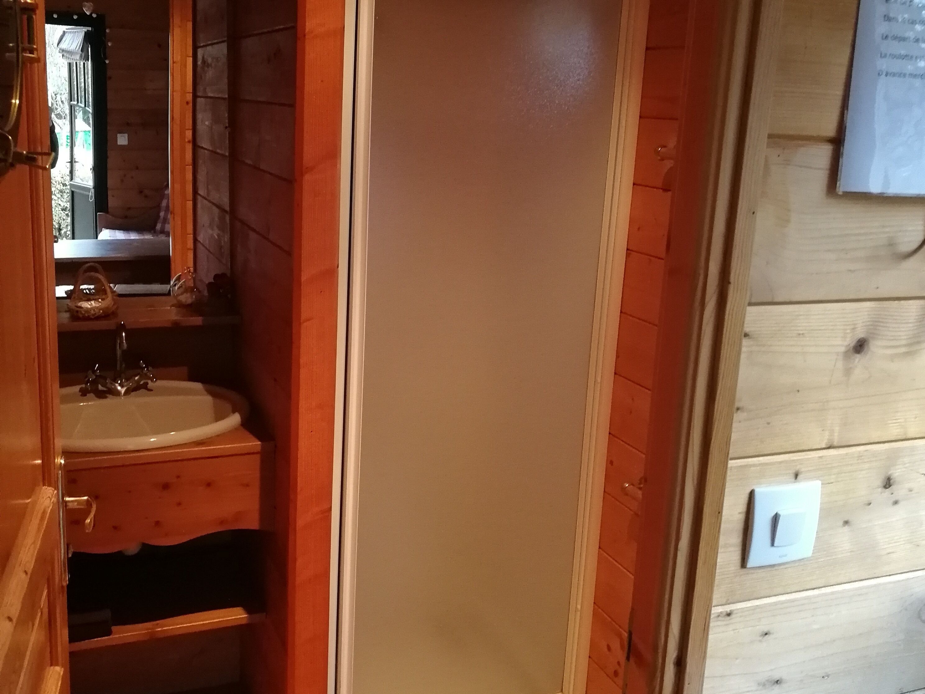 A wooden bathroom with a sink, mirror, and a towel rack.