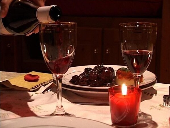 A table with two wine glasses, a candle, and a plate of food. - Le Relais de Maufront (Ouagne)