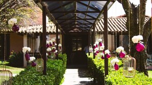 A covered walkway with hanging flower arrangements and birdcages. - Engenho da Serra Hotel & Ecoresort (Capitólio)