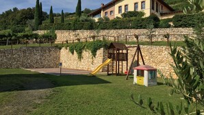 A house with a stone wall, a playground with a slide, and a grassy yard. - La Bella Vigna (Marano di Valpolicella)