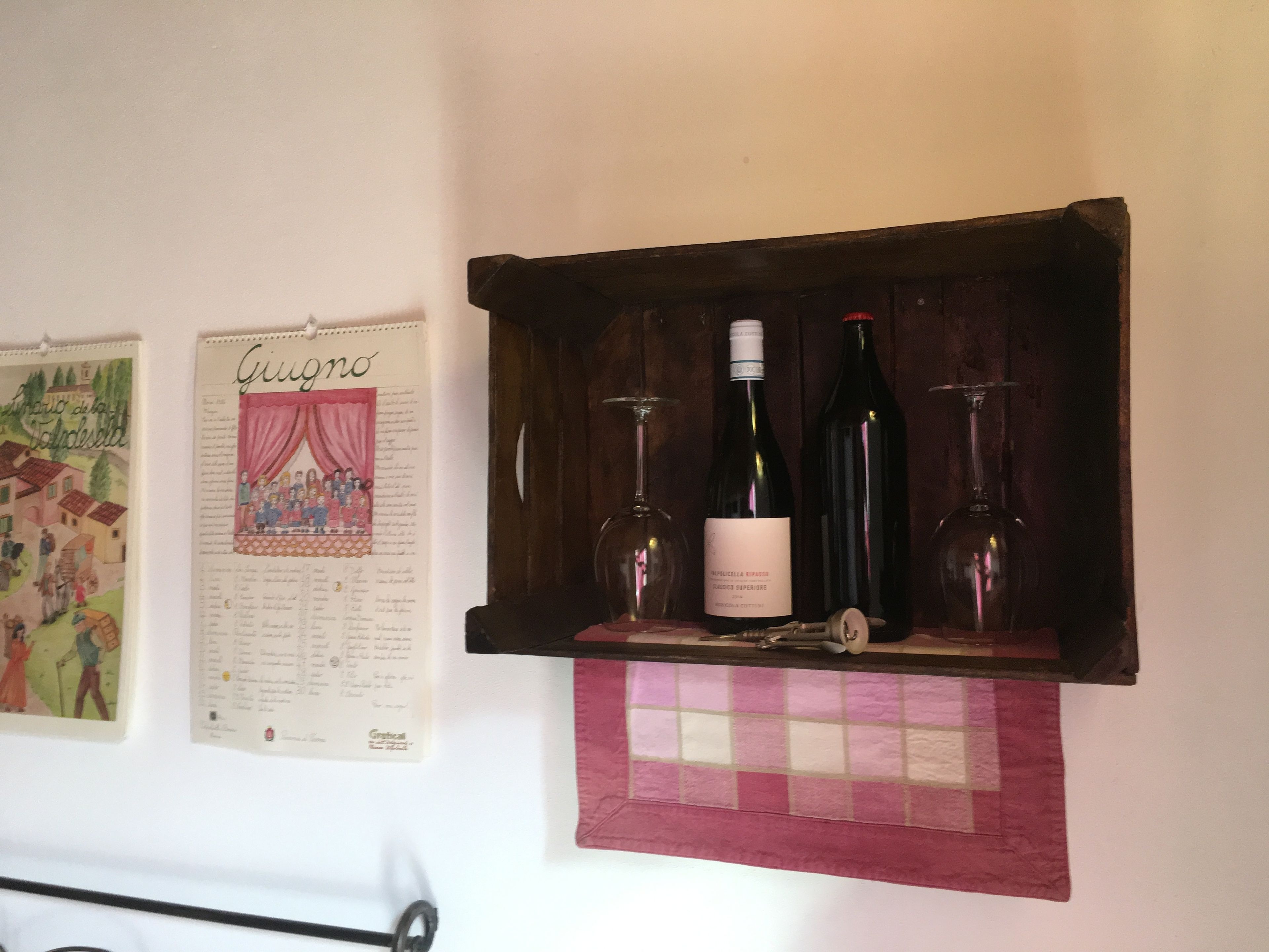 A wall with a corkboard displaying a menu and a wine rack with bottles.