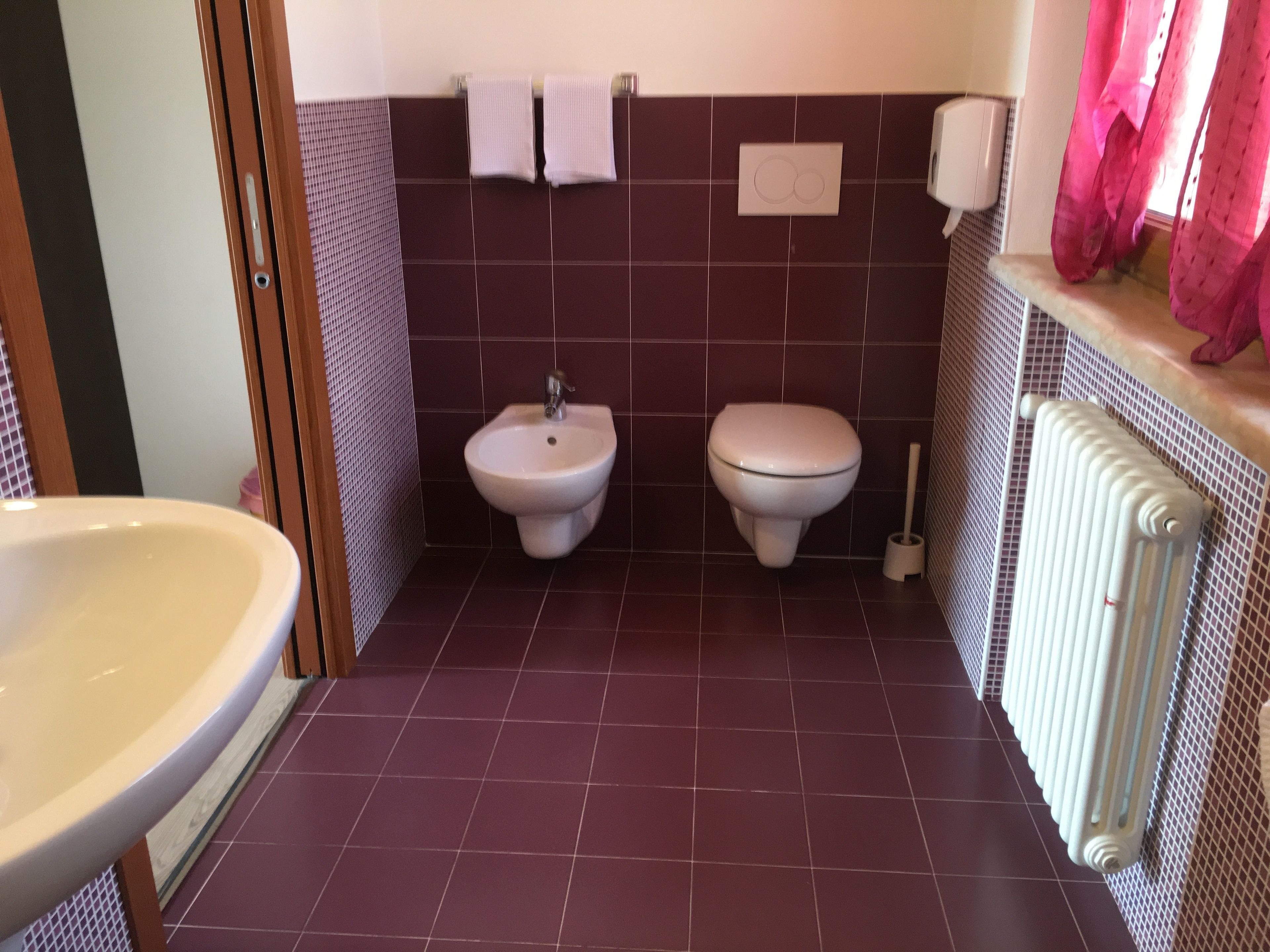 Een badkamer met een hygiëneschuimer, toilet en wastafel.