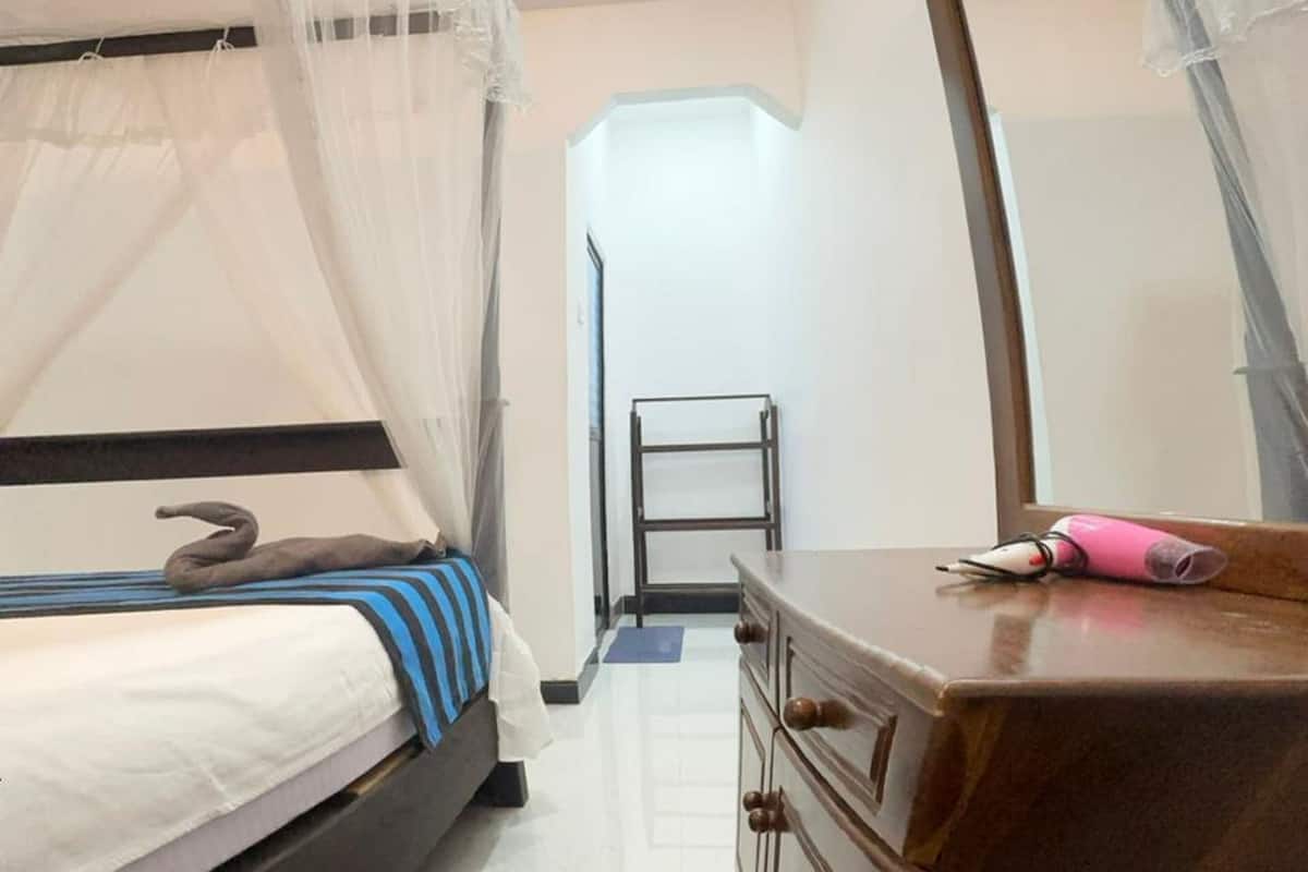 A bedroom with a bed, a dresser, a mirror, and a bedside table.