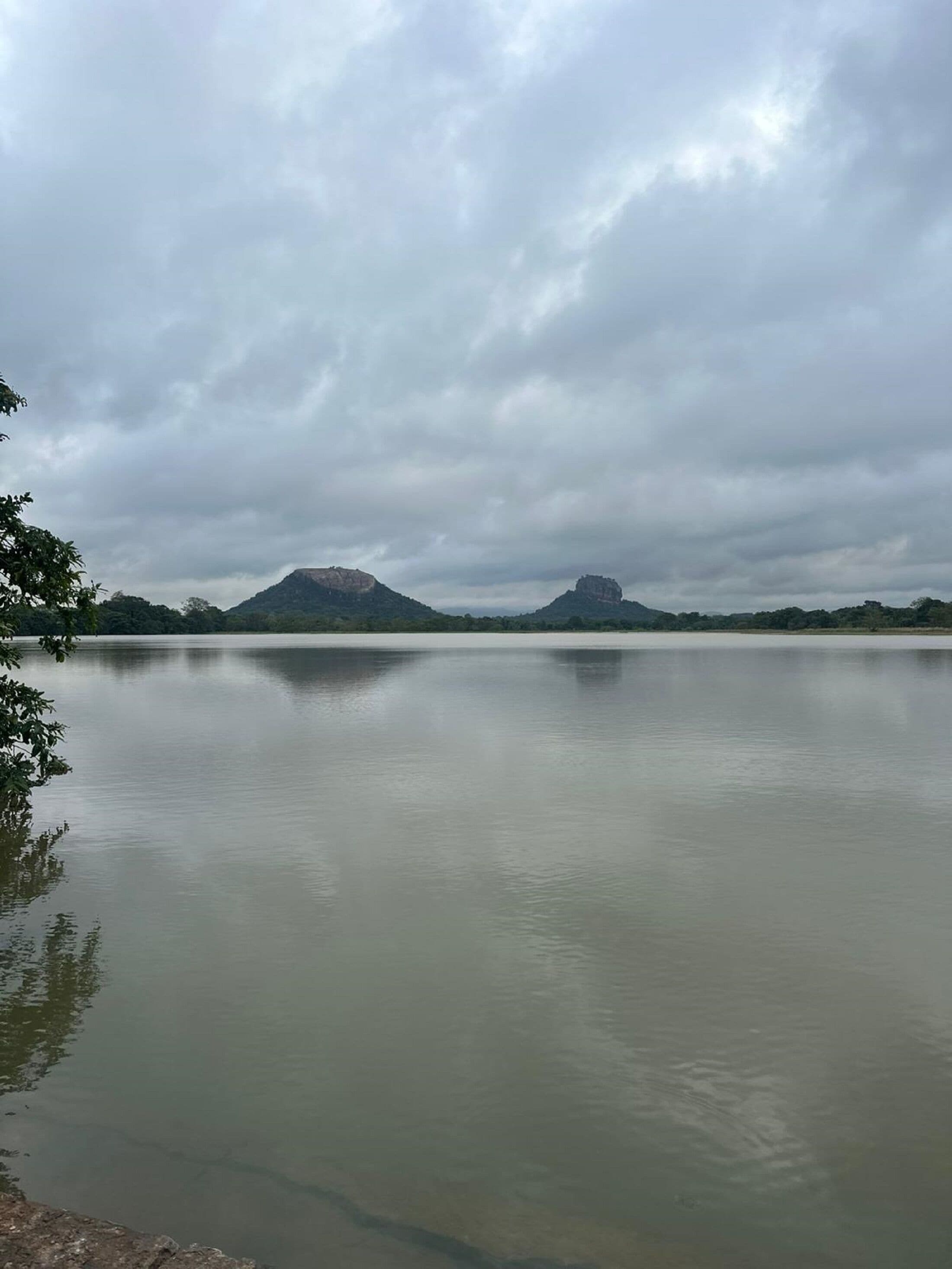 A calm lake with mountains in the distance and overcast sky.