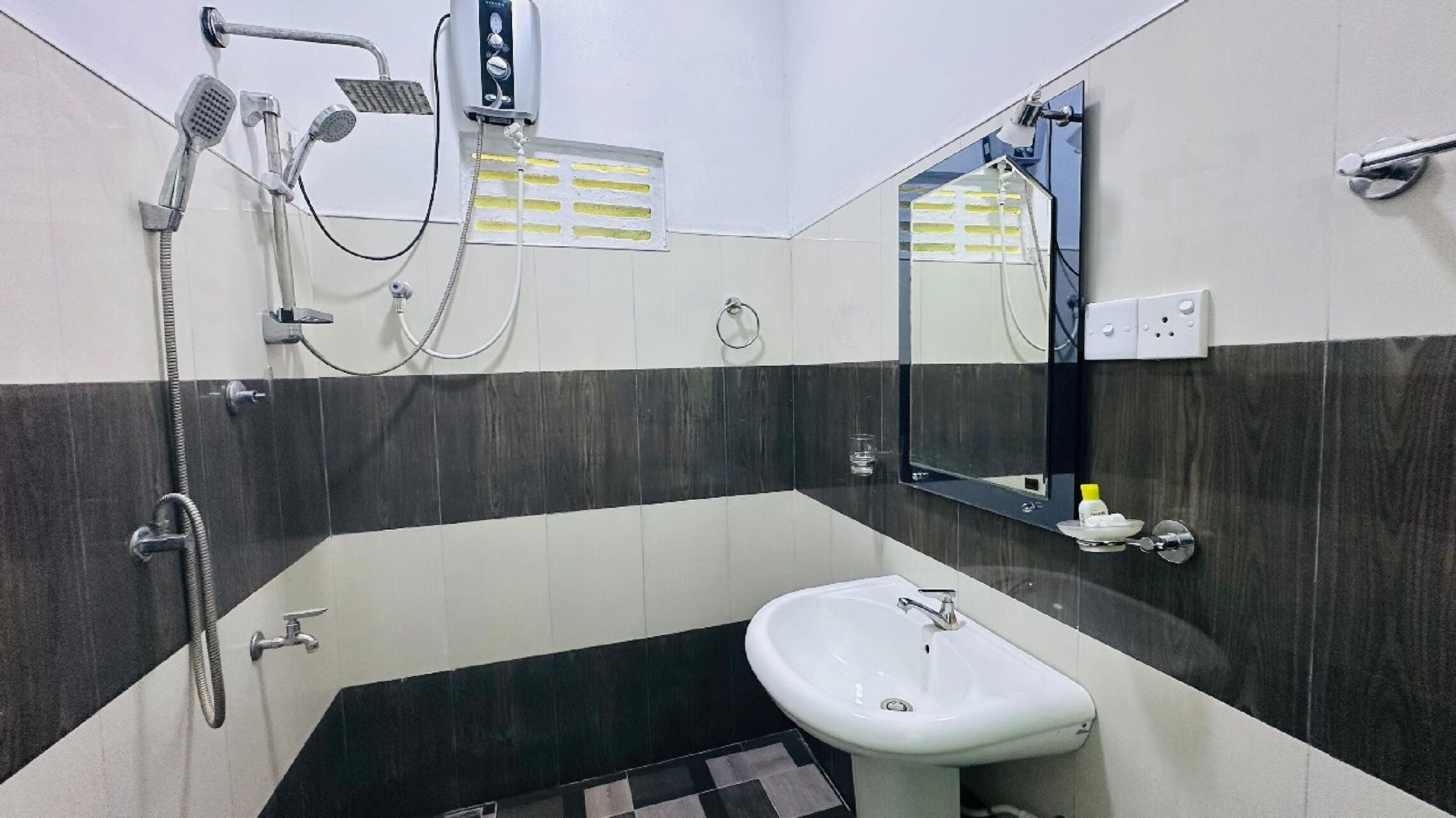 A bathroom with a white sink, a mirror, a shower with a handheld showerhead, and a towel rack.
