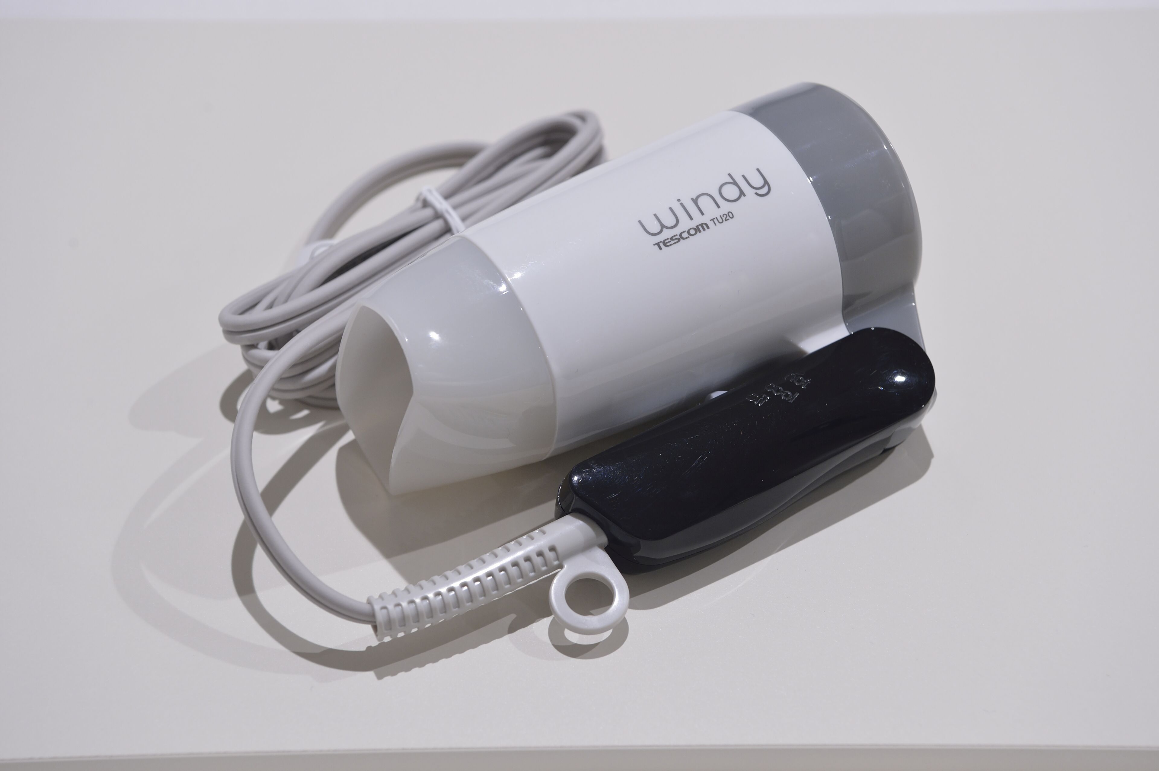 A white and black portable speaker with a coiled cable and a white USB charging cable.