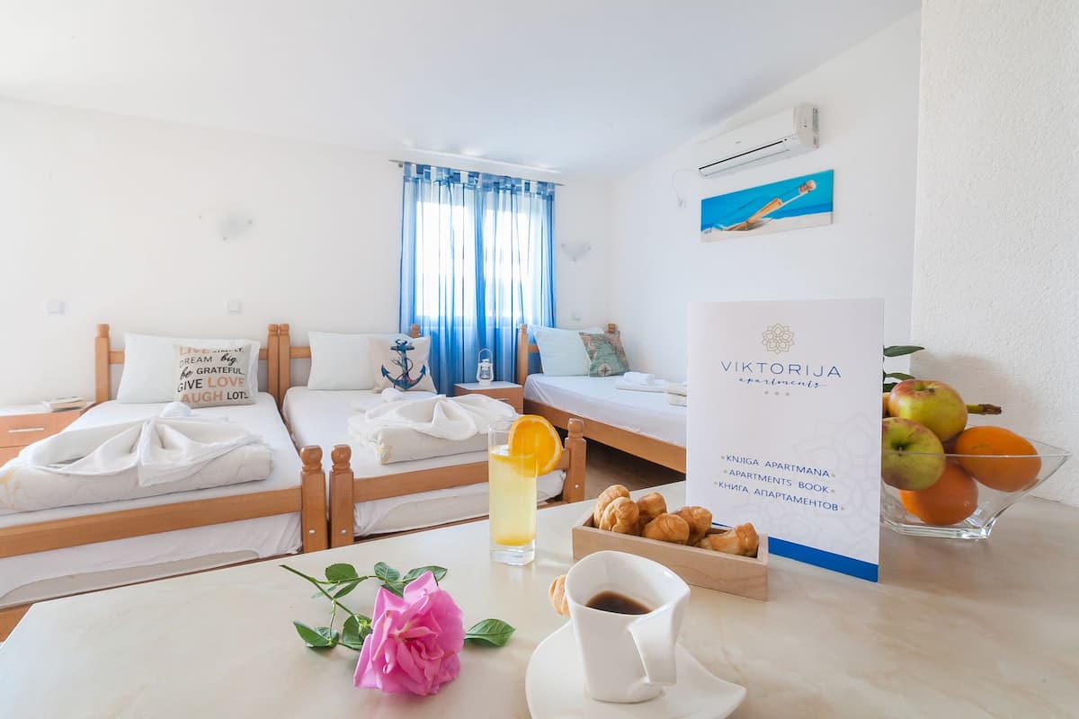 Une chambre d’hôtel avec un lit, une table sur laquelle se trouve une boisson, un bol de fruits et un panneau.