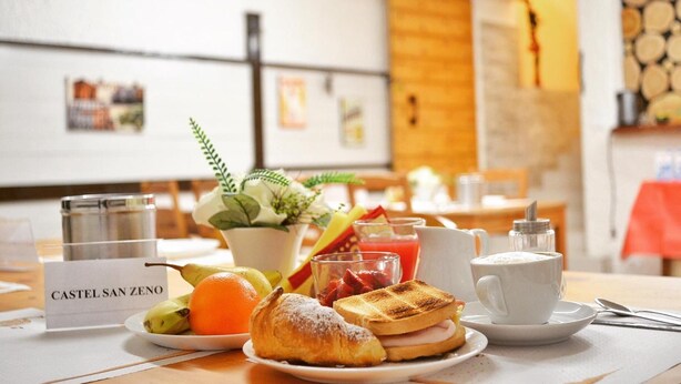 A breakfast setting with a plate of food, a cup of coffee, and a sign reading "CASTEL SAN ZENO". - La Villa (Montagnana)