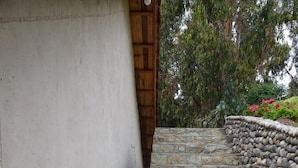 Un escalier en pierre menant à une porte en bois, le tout entouré d’un mur de pierre et de verdure.