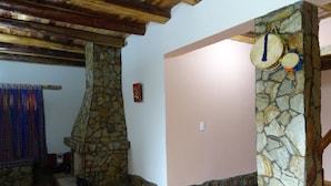 Une cheminée en pierre avec un conduit de cheminée en pierre, un plafond en bois et un mur en pierre orné d’une décoration suspendue.
