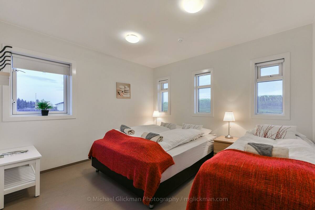 Een slaapkamer met twee bedden, een bureau en een raam.