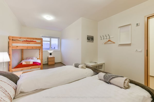 Ein Schlafzimmer mit Etagenbetten, einem Nachttisch, einer Lampe, einem kleinen Schreibtisch, einem Spiegel und einem Fenster mit Bergblick.