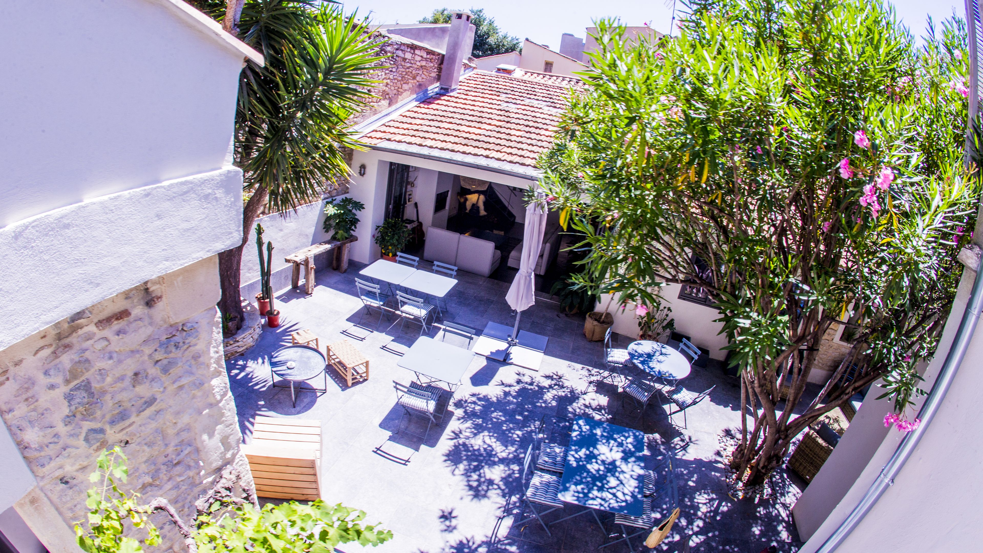 An outdoor patio with tables and chairs, surrounded by potted plants and a stone wall.
