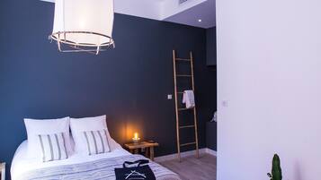 Een moderne slaapkamer met een bed, nachtkastje, lamp, ladder en een potplant.