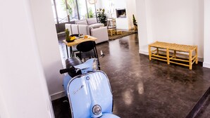 A modern interior with a blue scooter, a wooden bench, and a dining area with a table and chairs. - Antichambre (Nîmes)