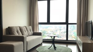 Una sala moderna con un sofá, una mesita redonda y un televisor sobre un mueble de madera.
