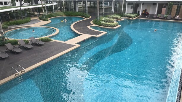 Una amplia piscina cubierta con múltiples carriles y una terraza circundante con sillones de descanso.
