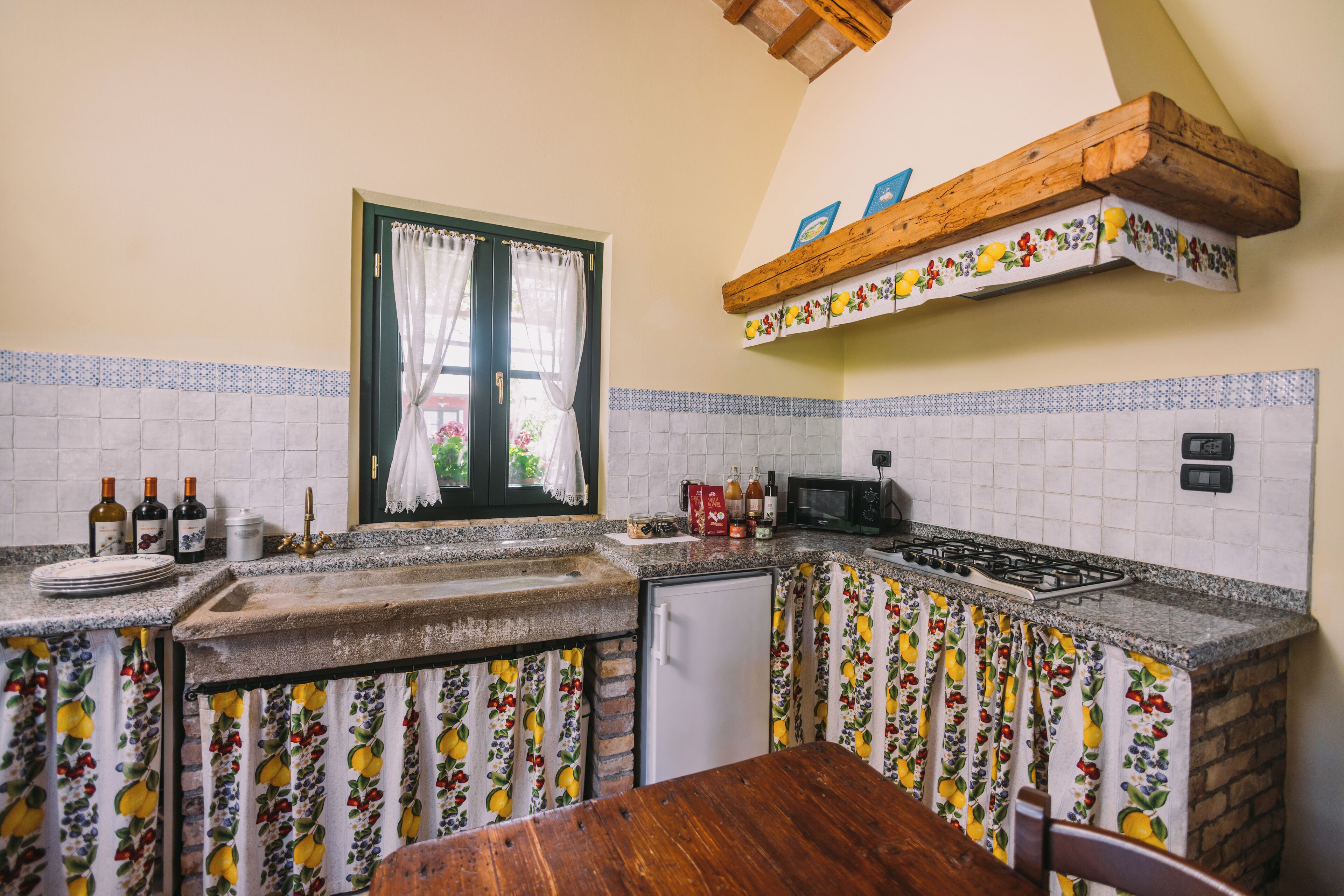 A kitchen with a wooden island, a window with curtains, a microwave, and a stove.