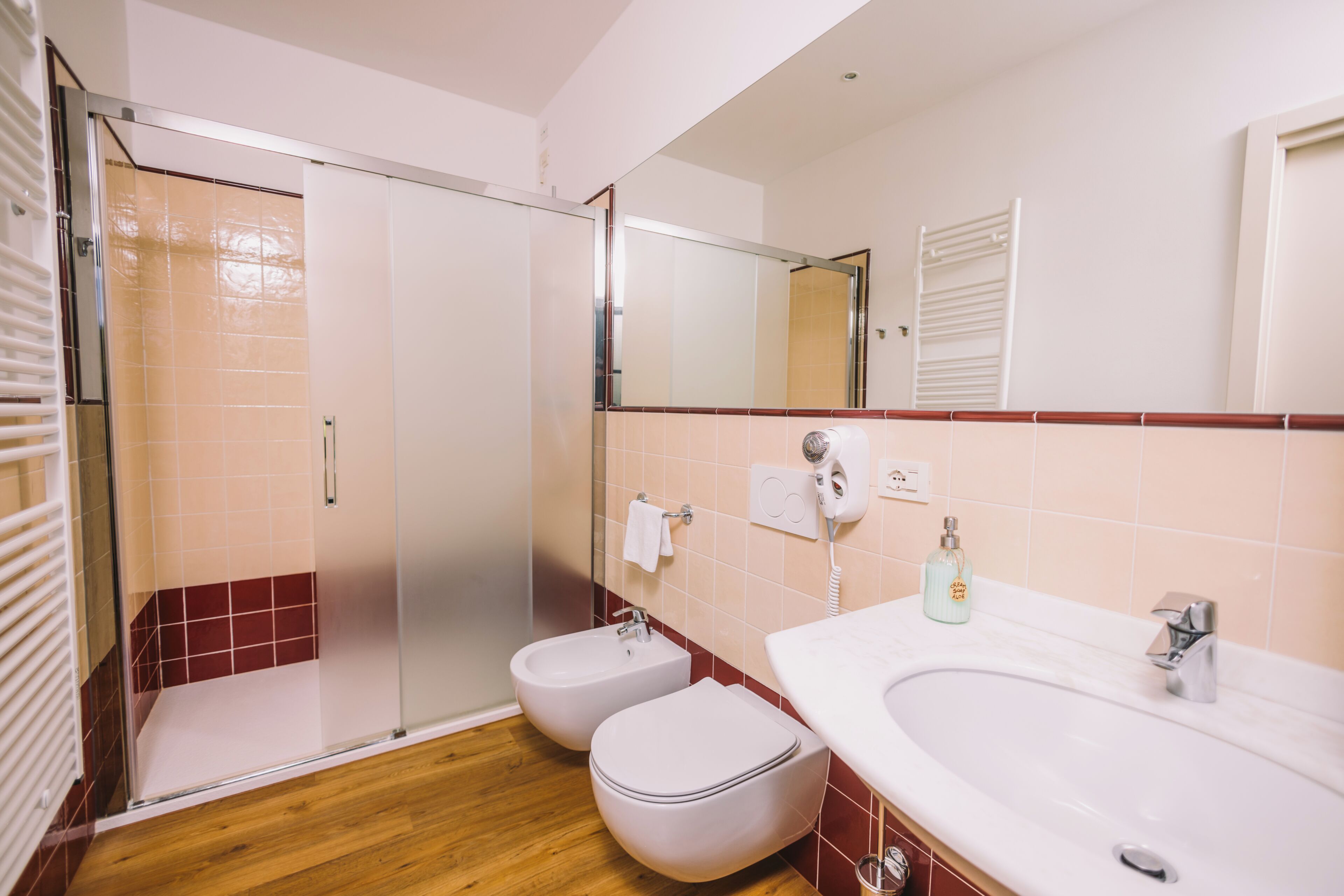 A bathroom with a shower, two toilets, a sink, and a mirror.