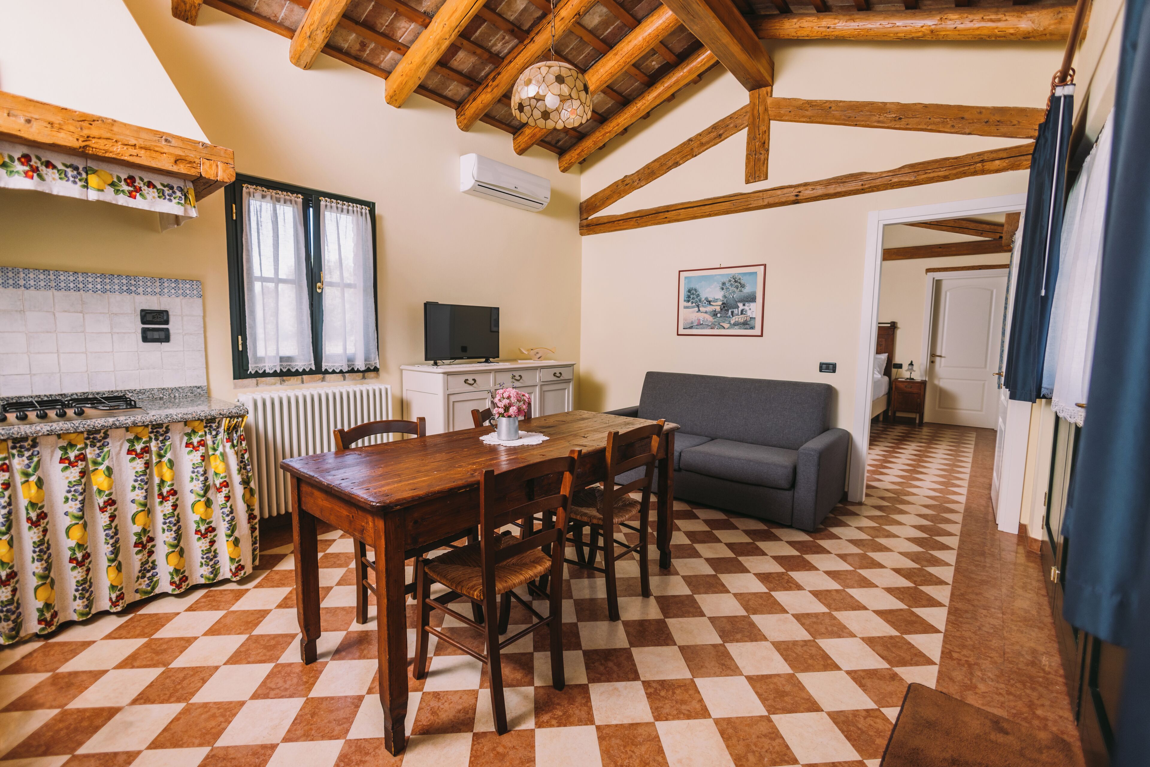 Una cocina con una mesa de madera, sillas, un sofá y piso a cuadros.