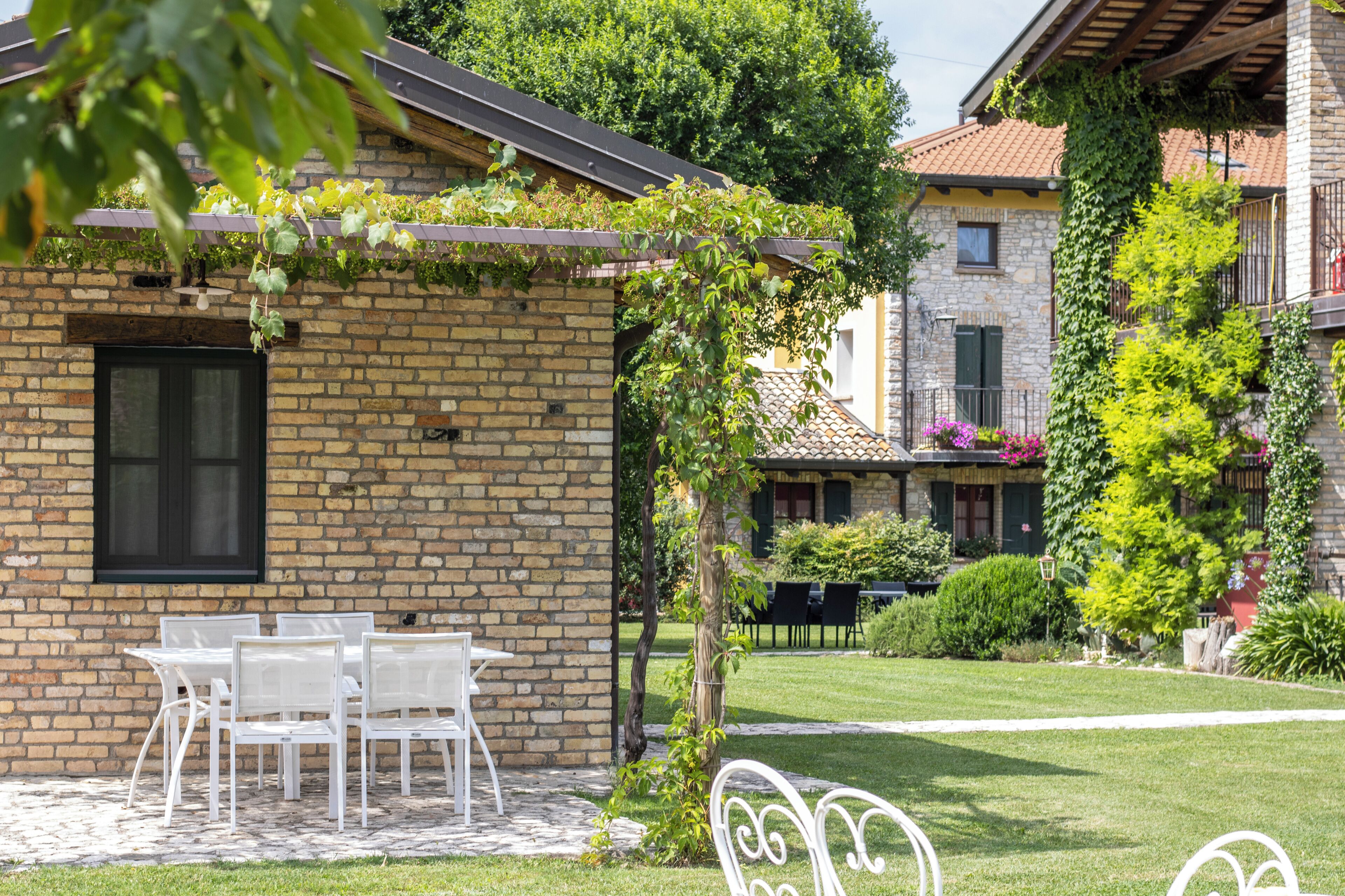 Um edifício de tijolos com pérgola, área de estar externa e um jardim bem cuidado.