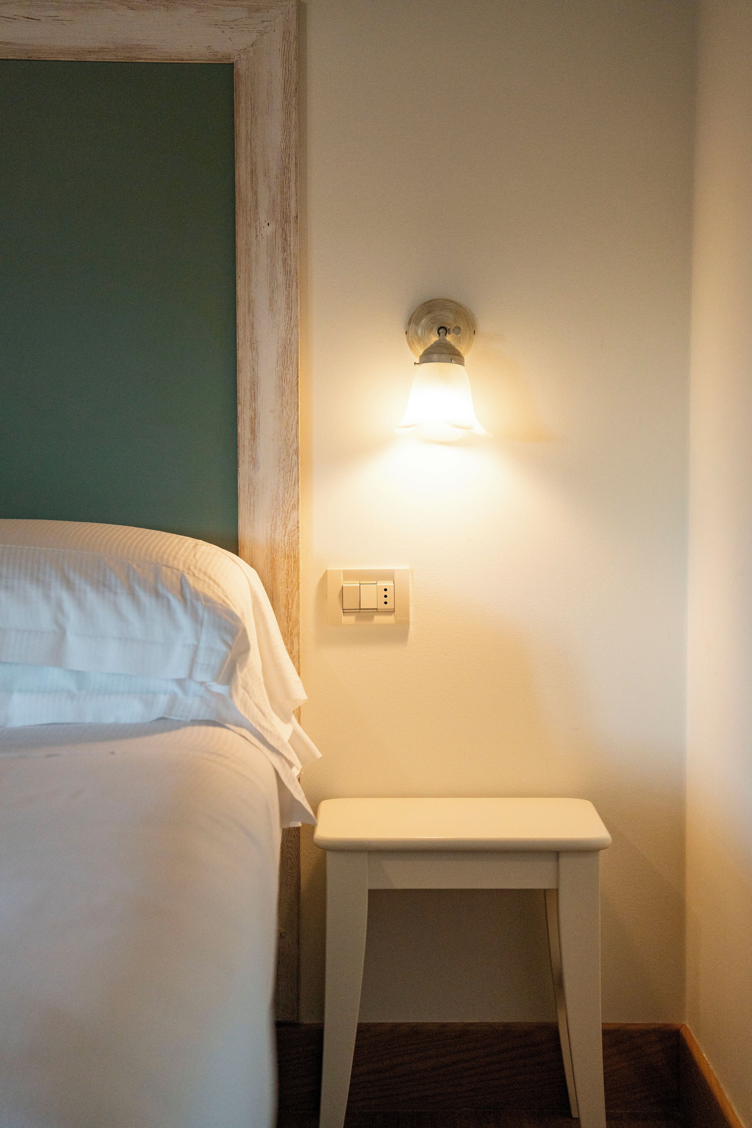 A neatly made bed with white linens in a small room.