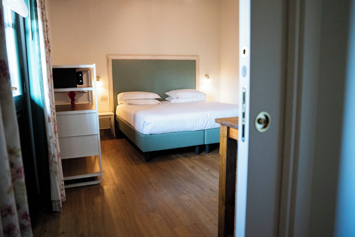 Un dormitorio con cama, mesitas de noche y un pequeño escritorio.