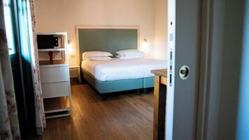 Un dormitorio con cama, mesitas de noche y un pequeño escritorio.