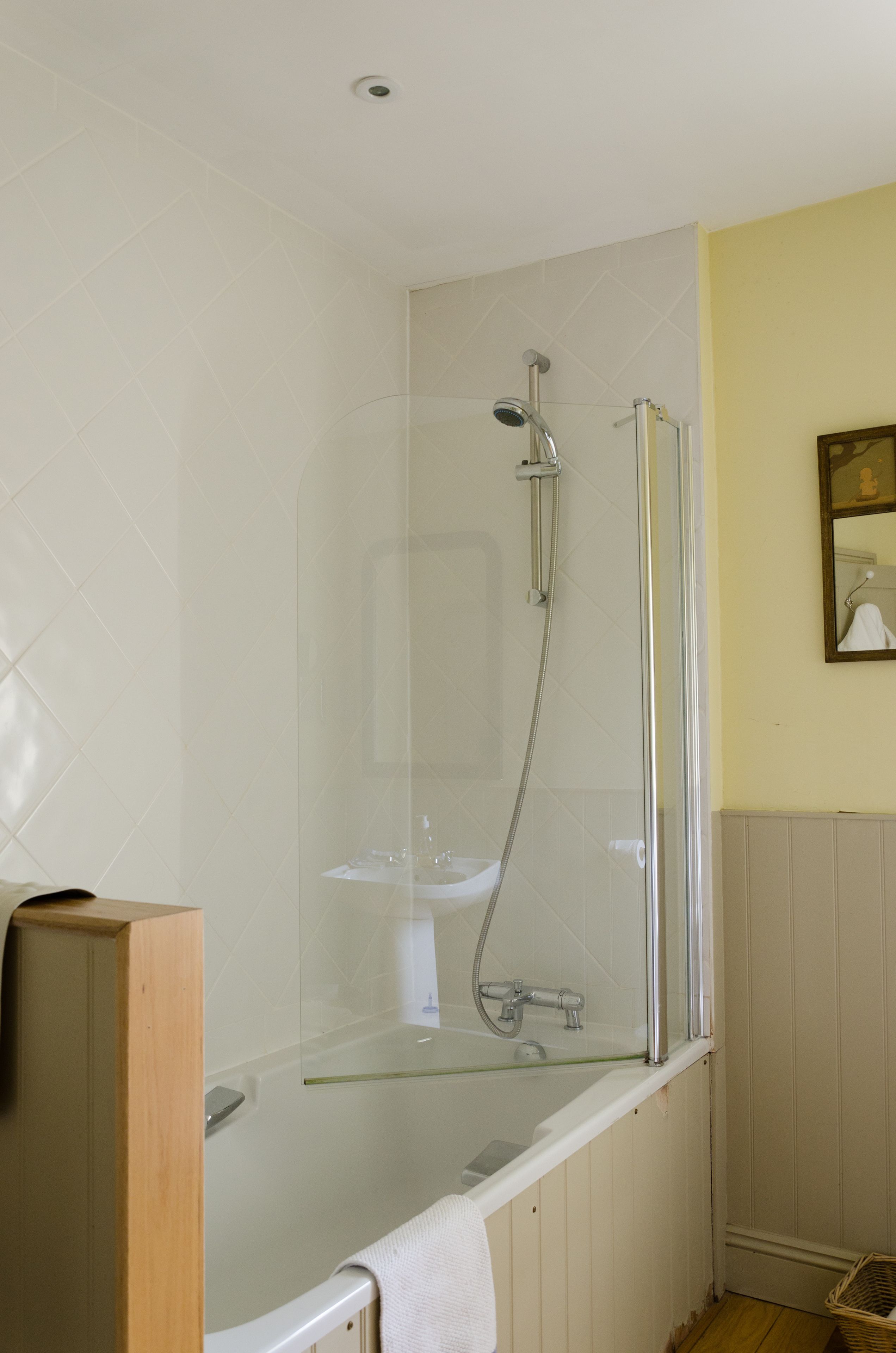 Un baño moderno con ducha envuelta en vidrio, una bañera blanca y un armario de madera.