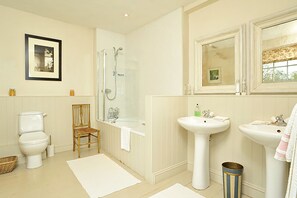 A bathroom with a toilet, shower, sink, and a framed picture on the wall. - Heron House (Tiverton)