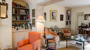 A well-furnished living room with a bookshelf, a sofa, a coffee table, and a chair. - Heron House (Tiverton)