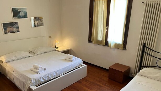 A bedroom with a bed, a nightstand, a dresser, and a window with curtains. - Il Cielo di Lucio (Pisa)
