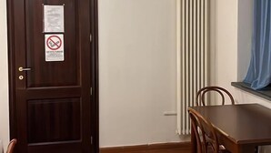 A room with a wooden door, a radiator, a ceiling fan, and a dining table with chairs. - Il Cielo di Lucio (Pisa)