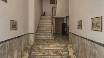Un escalier en marbre, avec un sol carrelé, mène à un palier.