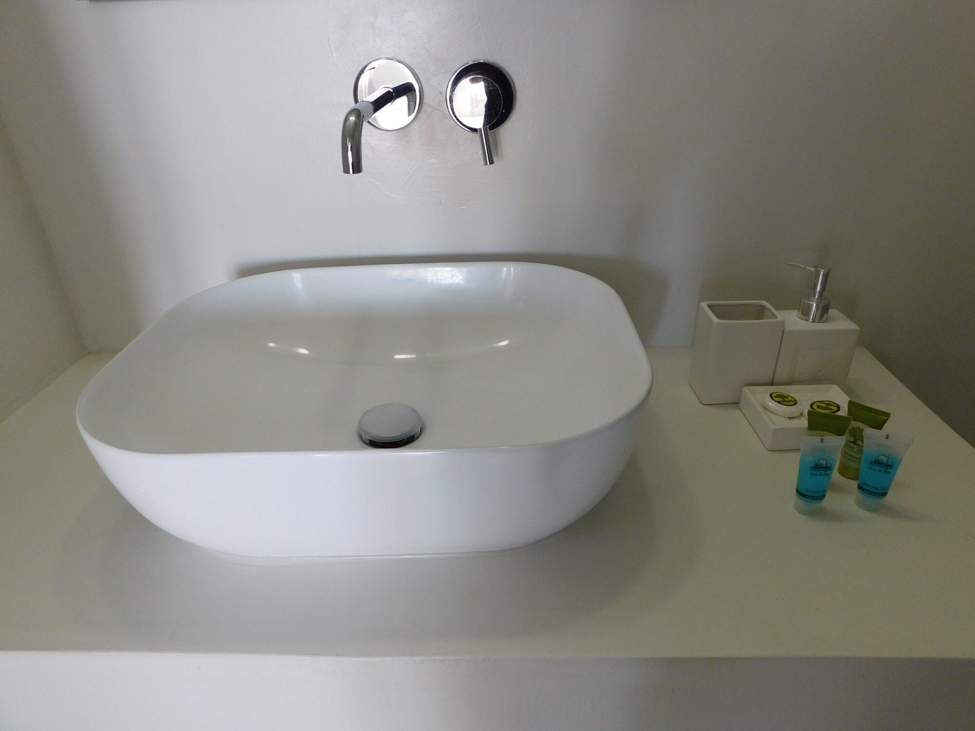 Ein Badezimmer mit einem weißen Waschbecken, zwei Wasserhähnen und einer Seifenspender.