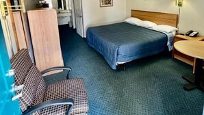 A hotel room with a bed, desk, chair, and a small table.