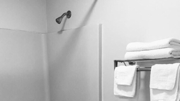 A bathroom with a bathtub, toilet, and a towel rack with folded towels.