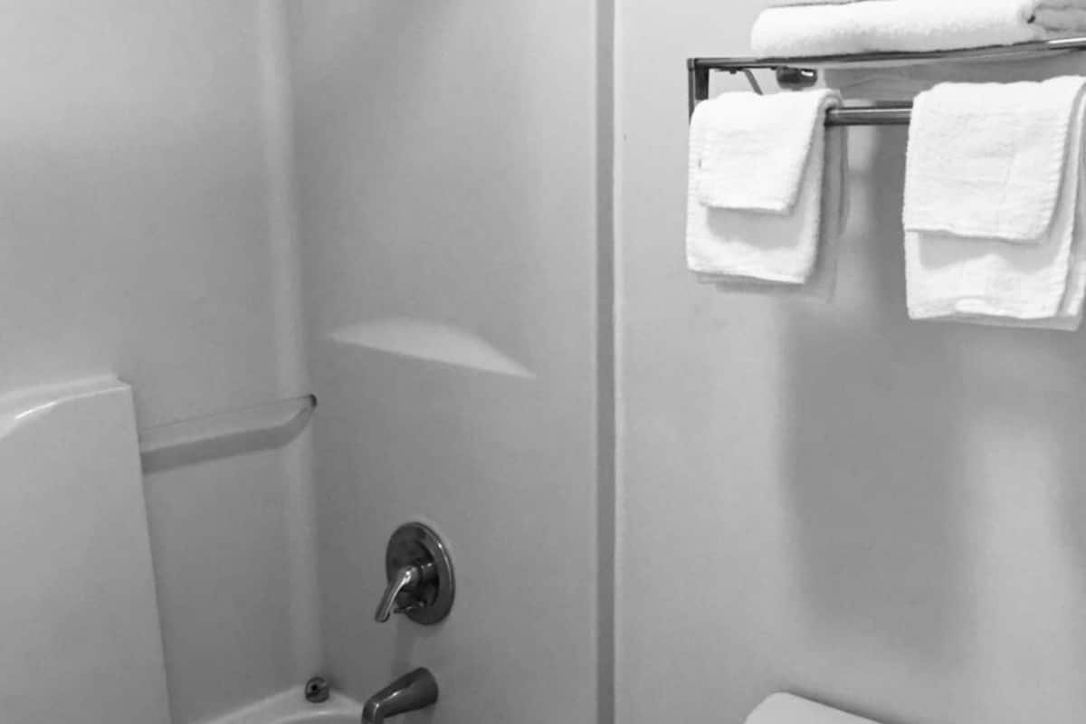 A bathroom with a bathtub, toilet, and a towel rack with folded towels.