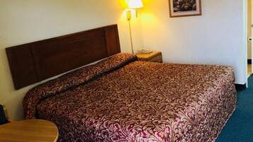 Habitación de hotel con una cama grande, una mesita de noche, una lámpara y un cuadro en la pared.