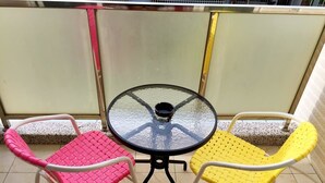 A small round table with a glass top surrounded by two chairs, one pink and one yellow, on a tiled floor. - Star to travel B&B (Hengchun)