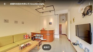 A modern living room with a sofa, a coffee table, a reception desk, and a flat-screen TV. - Star to travel B&B (Hengchun)